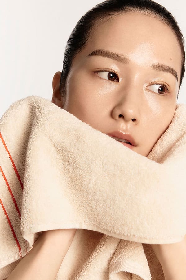 A model wiping her face with a towel