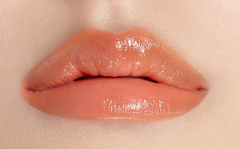 A model with Perfecting Lip Color NO. 520 AMBER applied three times