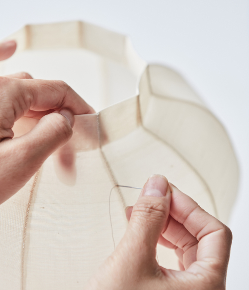 장인이 얇은 소재를 손으로 다루며 달항아리 형태의 구조를 제작하고 있다