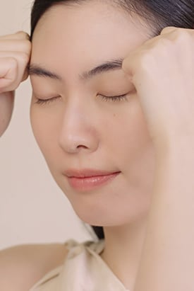 눈을 감고 이마를 부드럽게 마사지하는 여성의 모습은 설화수 자인생 진액 크림의 흡수를 돕는 방법을 보여줍니다.