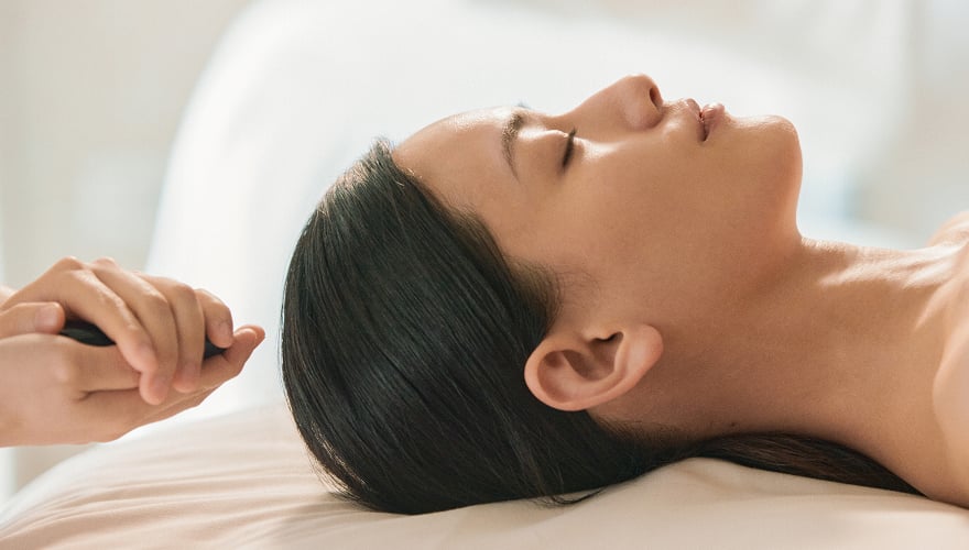 마사지 베드에 하늘을 보고 누워있는 여성